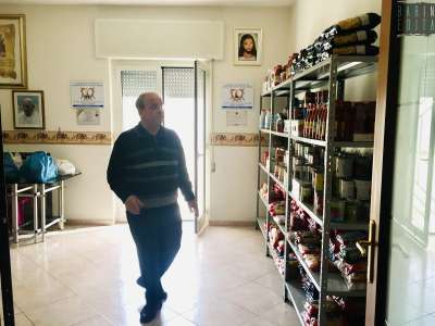 Una volta entrati ci mostra la stanza allestita con una serie di scaffali pieni di cibo da donare: pasta, pelati, latte, farina e olio soprattutto
